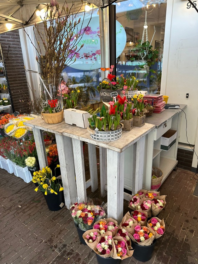 Tafel vol bloemen en boeketten bij de ingang van de winkel